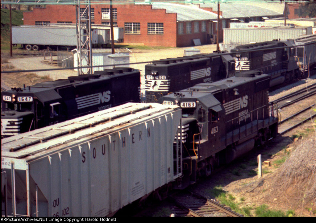 NS 4163 shoves cars while a string of SD's pulls a grain train out of the siding